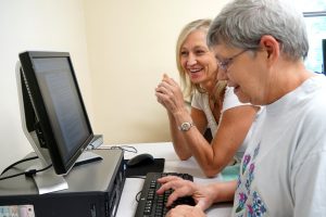 woman helping old woman in the computer